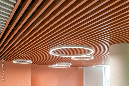 Wooden panels and round lights Circular pendant lights on wooden slats, modern ceiling interior design, harmony of warm colours and architectural lighting. Real photo