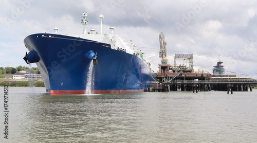 A large tanker ship with a blue hull sits anchored at the oil jetty