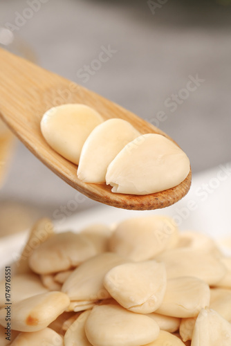 Tableau sur toile Peeled Sliced Almonds on Wooden Spoon with Scattered Nuts - Healthy Natural Ingr