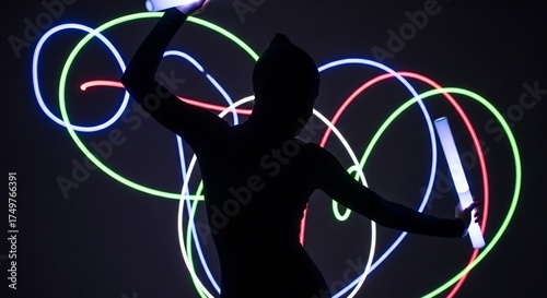 Dancer performing with illuminated sticks against colorful light trails. Artistic dancer creates vibrant movements while manipulating glowing sticks, showcasing creativity and energy.