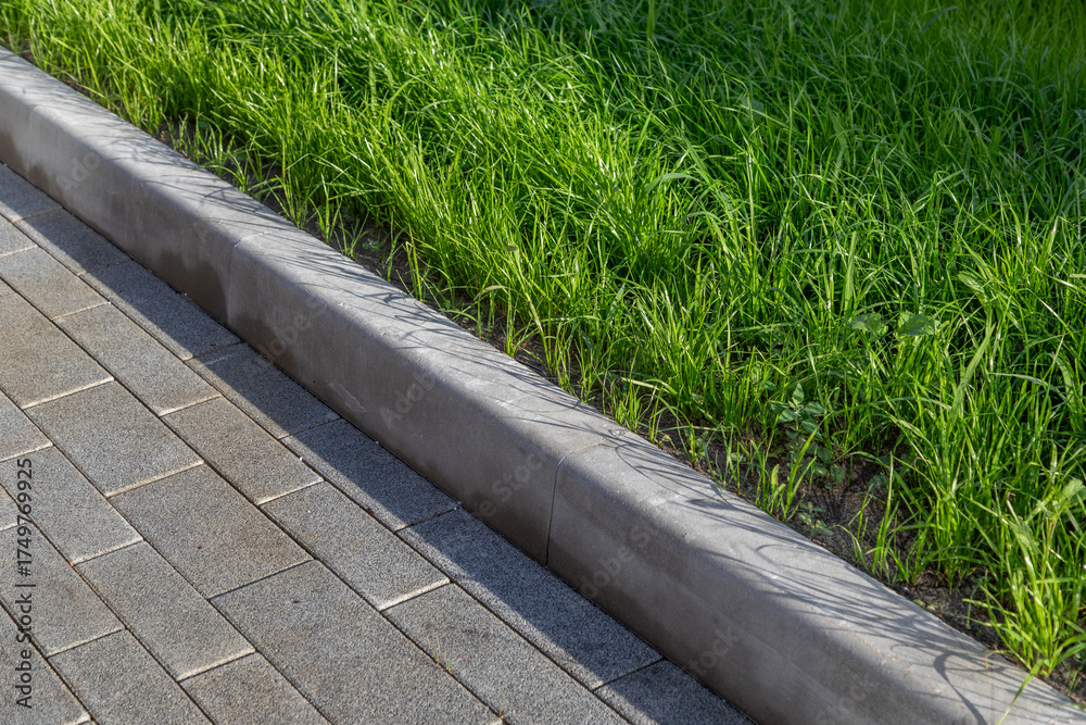 Obraz premium Paving with curb and green lawn on landscaped grounds. Diagonal arrangement