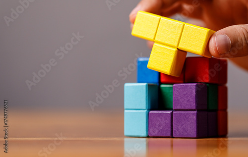 Person assembling a cube puzzle with colorful blocks. Concepts of problem solving, teamwork, creativity, and education. Suitable for diverse des
