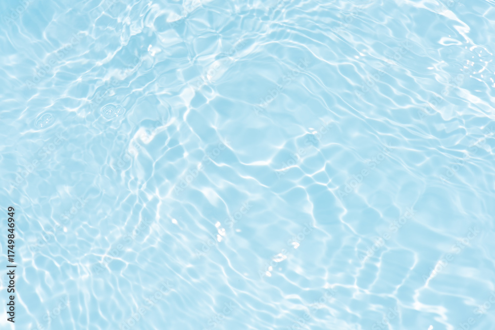 Obraz premium Blue water with ripples on the surface. Defocus blurred transparent blue colored clear calm water surface texture with splashes and bubbles. Water waves with shining pattern texture background.