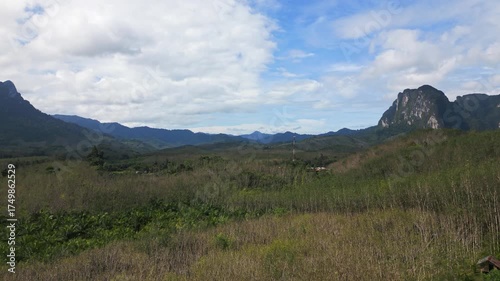 Aerial view of Khao Sok National Park in Thailand, showing lush jungle, palm plantations and majestic mountains rising in the distance under tropical sunlight