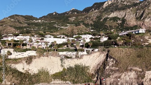 Beautiful coastal drone town shot of Ischia island in Italy with deep blue sea waves, cliffs and sunny weather. 