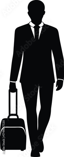 A male traveler wearing a smart suit walks forward while pulling his small wheeled luggage