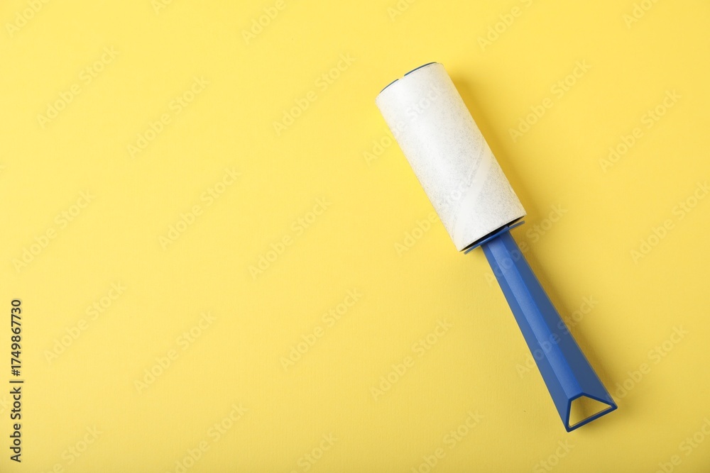 Fototapeta premium One lint roller on yellow background, top view. Space for text