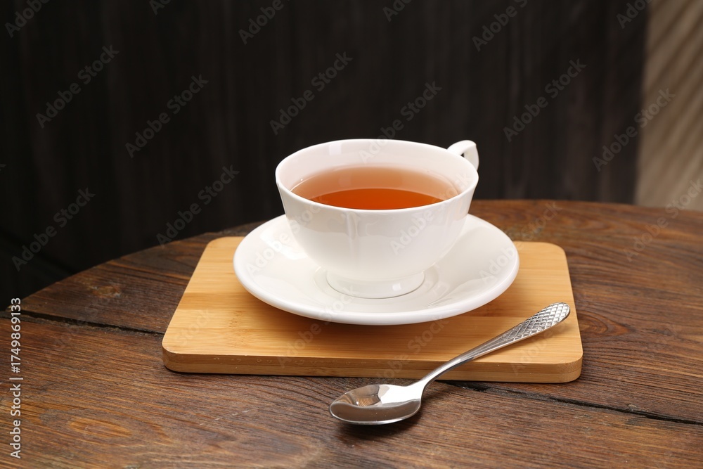 Obraz premium Aromatic black tea in cup and spoon on wooden table, closeup