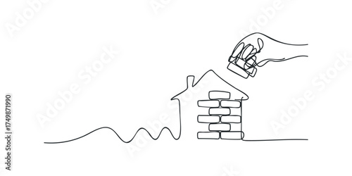 Hand placing last brick on simple house outline