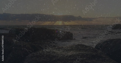 Sun sinking over horizon, casting glow on ocean waves crashing on rocky seashore under cloud layer © vectorfusionart