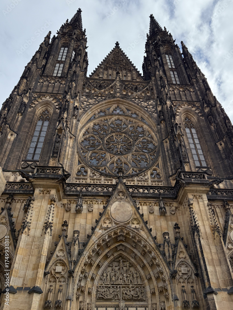 Fototapeta premium Low-angle view of the soaring Gothic buttresses and stained glass windows of St. Vitus Cathedral, emphasizing monumental height for Prague tourism, architectural studies, or European heritage marketin