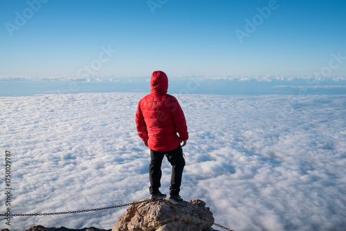 Man reaching mountain top viewing cloudscape panorama