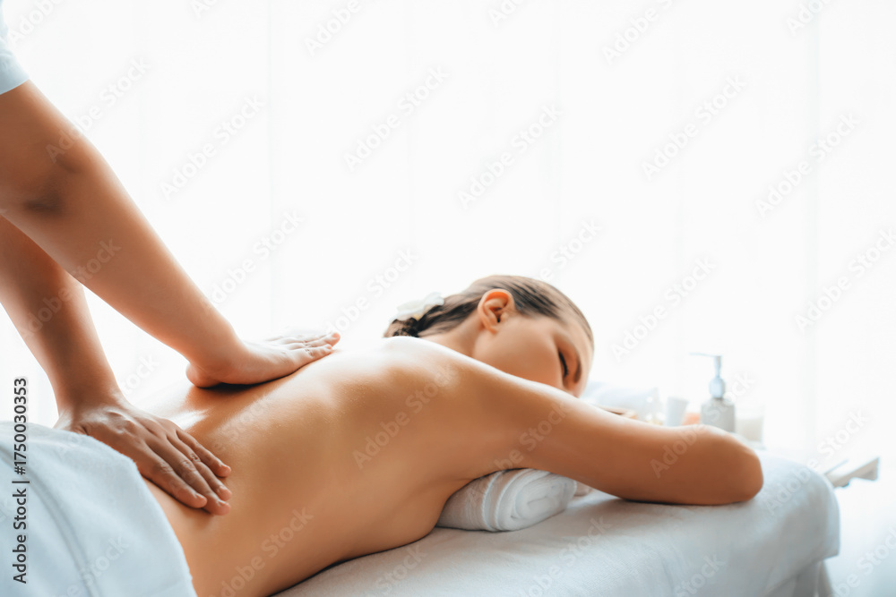 Fototapeta premium Caucasian woman customer enjoying relaxing anti-stress spa massage and pampering with beauty skin recreation leisure in day light ambient salon spa at luxury resort or hotel. Quiescent