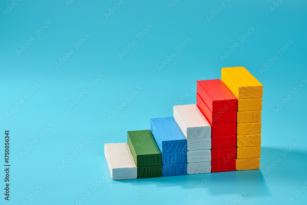 Obraz premium Colorful wooden blocks create a staircase pattern on a blue background showcasing creativity and learning in educational playtime, copy space.