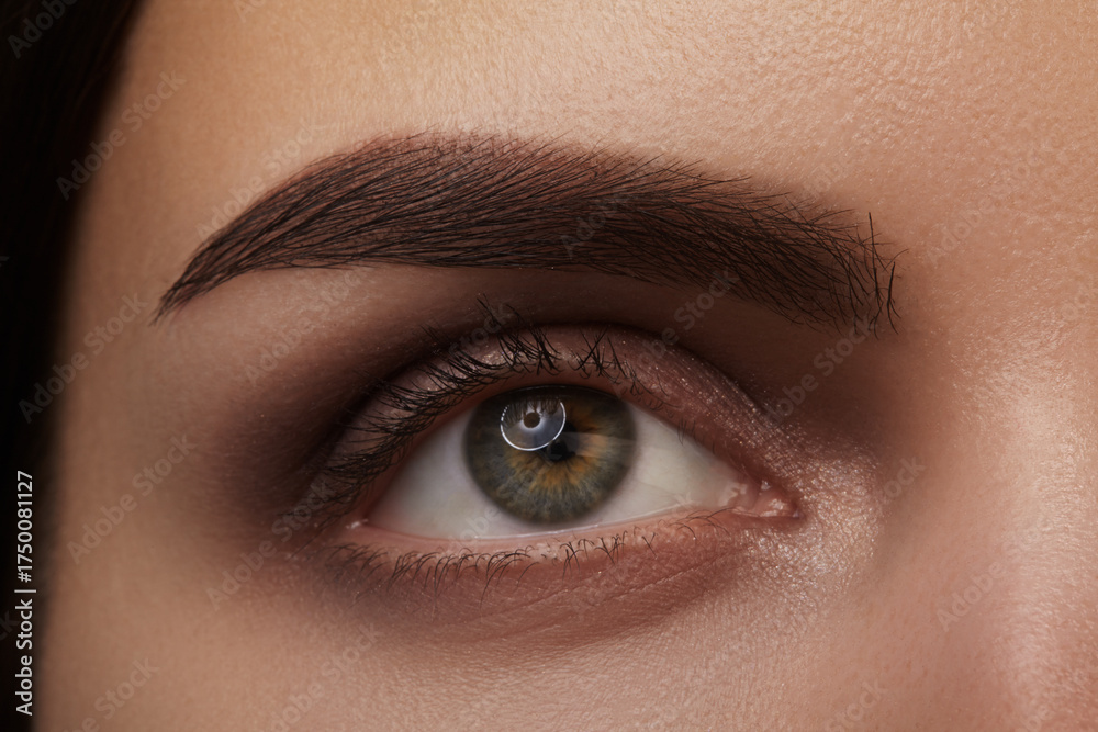 Fototapeta premium Studio close-up of a hazel eye and well-groomed eyebrow, soft lighting emphasizing skin texture, lashes and iris detail. Suitable for beauty and brow grooming visuals