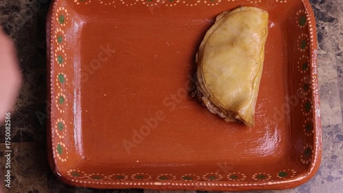 Hands arranging authentic mexican steamed tacos, or tacos de canasta, on a traditional clay plate