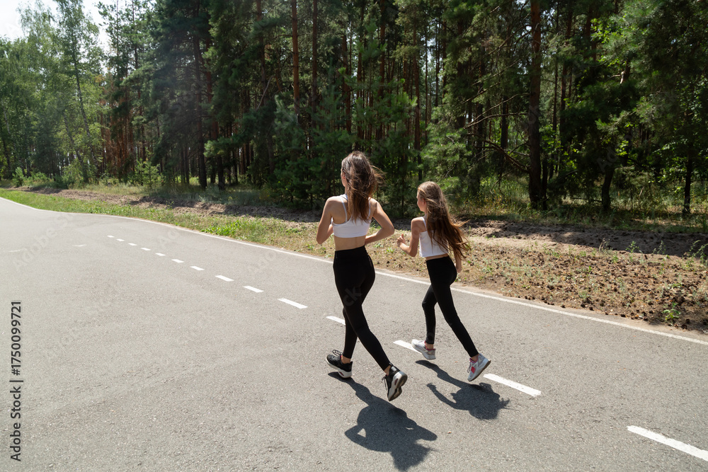 Fototapeta premium Happy active mother and child jogging outdoors, running in forest
