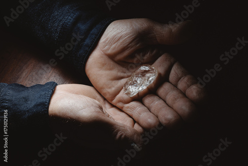 Bild auf Leinwand Wrinkled textured hands of male prospector holding raw diamond