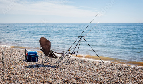 Pair of fishing rods set up on beach for sea fishing with no people in Dorset, UK