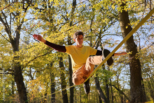 man in yellow t-shirt doing slackline in autumn park