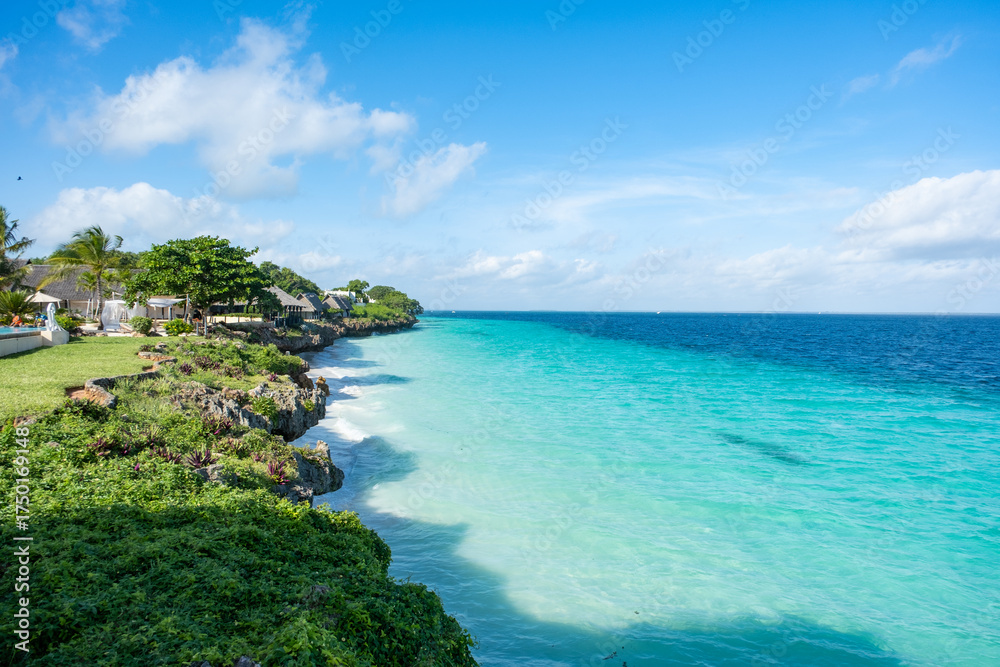 Fototapeta premium Idyllic tropical beach in Nungwi, Zanzibar, with white sand, turquoise waters, and palm trees under a clear blue sky. Perfect paradise escape in East Africa.