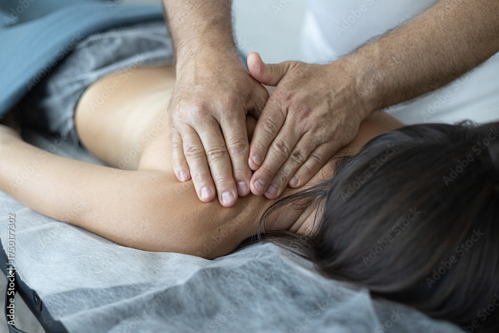 Fototapeta premium Close-up view of a professional massage therapist performing a relaxing back massage for a woman lying on a massage table. Wellness, body care, and relaxation concept