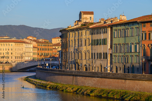 View of the Arno River with the Ponte di Mezzo bridge and pastel-colored buildings in the historic center of Pisa, Italy