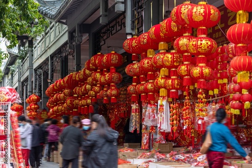 Vibrant Red Lanterns Adorned Street for Lunar New Year Celebration with Decorations People and Traditional Architectural Background