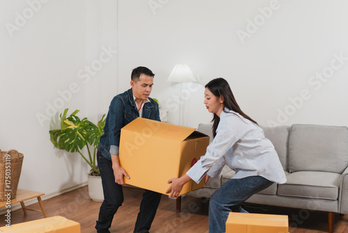 Young couple teamwork carrying large cardboard boxes unpacking in modern living room during home relocation process