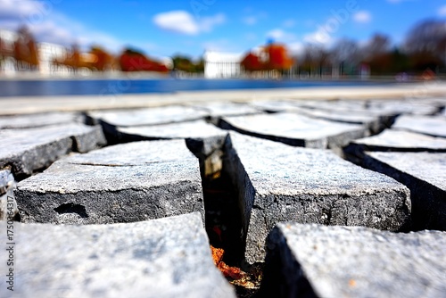 Close-up textured pavement, reflecting blurred autumn landscape