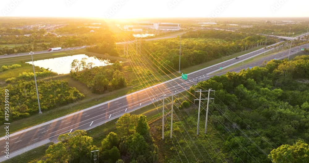 High voltage power lines on steel tower span across busy Florida highway with cars in motion. Electrical energy transmission over transportation route