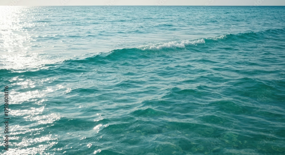 Obraz premium Sparkling turquoise ocean stretches towards a sunlit horizon, capturing ripples and small waves