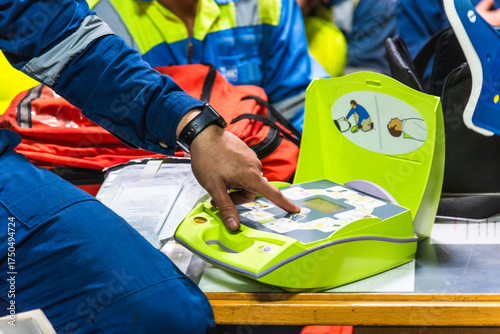 An Automated External Defibrillator (AED) is open on a table during emergency training on a cargo ship. 