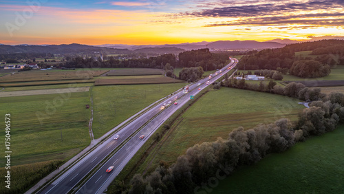 An aerial view of the highway cutting through the picturesque Slovenian countryside near Krtina village by Lukovica, bathed in the warm glow of sunset.