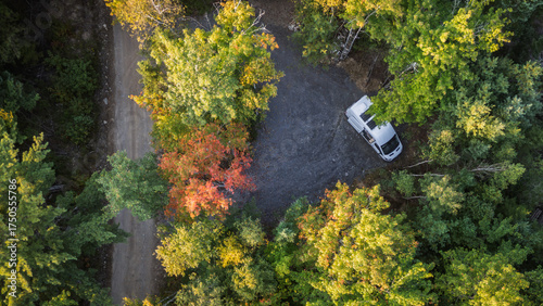 Aerial view of white campervan on dirt road in early autumn fore