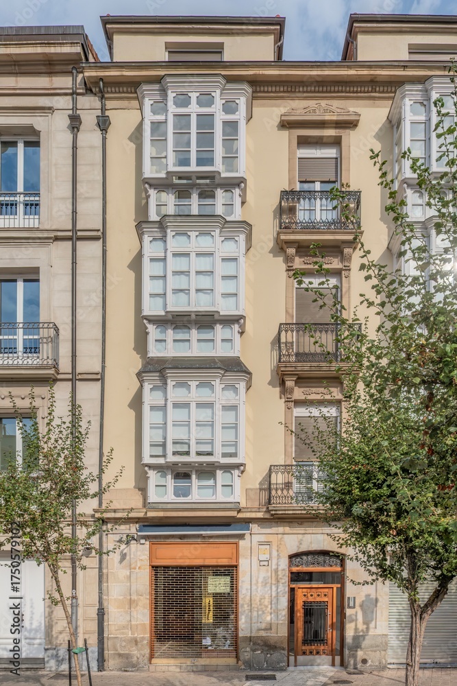 Fototapeta premium Traditional Spanish Building Facade with White Bay Windows and Iron Balconies