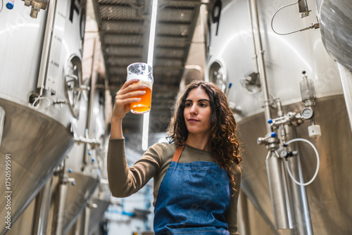 Foto Woman brewer evaluating beer quality, holding a tasting glass, standing in a mod