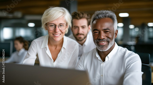 Collaborative Insight: A dynamic team collaborates closely at a laptop, showcasing teamwork and shared expertise within a modern office environment.