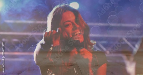 Singing singer holding handheld mic reaching toward audience on music stage with truss lights, haze