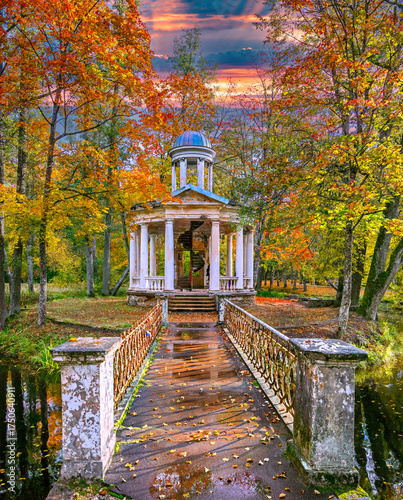 Late autumn in old public park, walking bridge and abandoned resting pergola