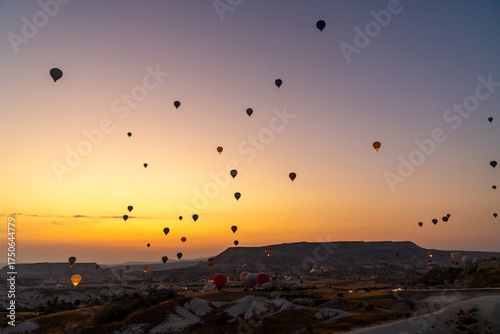 Hot air balloon flying over rocky landscape at sunrise in Cappadocia. Turkey