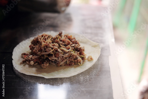 The freshly cooked savory filling for a Lumpia Basah Bogor, a popular Indonesian wet spring roll, sits on a wrapper, ready to be folded at a street food stall.