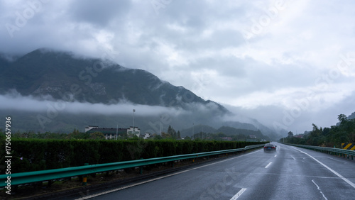 Misty mountain road with vehicle under overcast sky