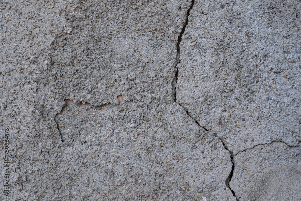 Fototapeta premium A close - up of a rough, cracked concrete wall with visible fissures
