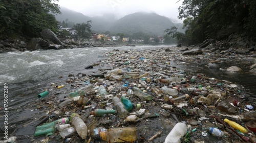 A river polluted with various plastic bottles and debris flows through a rural landscape. Fog covers the mountains creating a somber atmosphere as the waste accumulates along the banks.