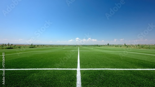 Bright Green Soccer Field Under Clear Blue Sky Surrounded by Open Landscape and Distant Mountains