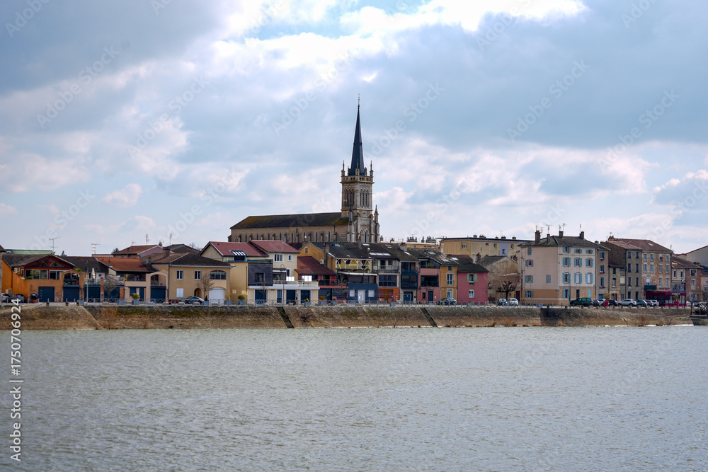 Fototapeta premium Panoramic cityscape of Macon France with historic church and colorful buildings along the Saone River under cloudy sky