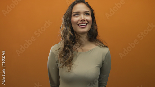 Фотография Woman smiling with thoughtful expression against vibrant orange background showi