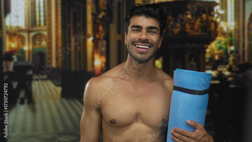 Tableau sur toile Man with bare chest holds blue yoga mat inside building while smiling broadly; irreverence defiance