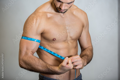 man measures bicep with measuring tape